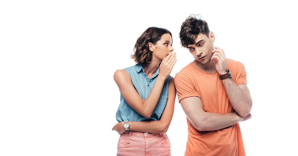 Junges Paar, sie flüstert ihm ins Ohr